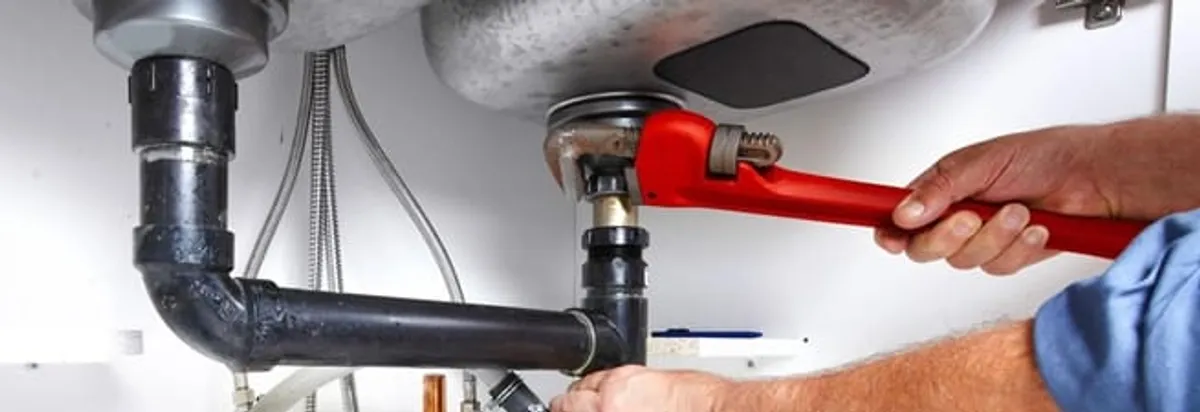 Garbage disposal repair technician tightening the sink drain and disposal connection in San Francisco, CA