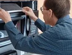 Appliance repair technician replacing a microwave vent filter in San Francisco, CA