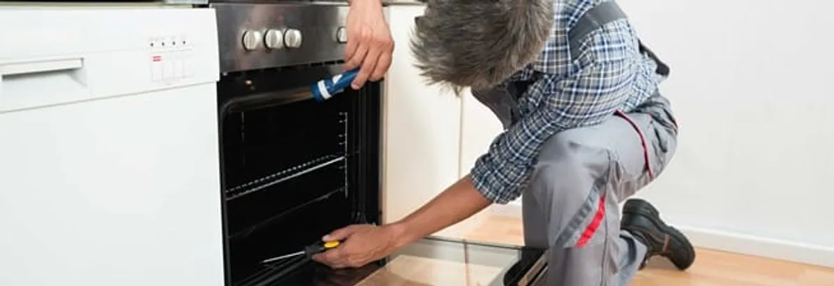 Oven repair technician inspecting and servicing an electric oven in San Francisco, CA