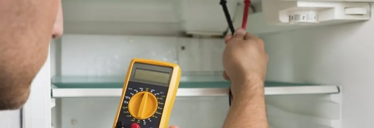 Refrigerator repair technician testing electrical components with a multimeter in San Francisco, CA